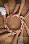 Hands, teamwork and circle with business people on a wooden table in the office closeup from above. Collaboration, synergy and an employee group or team together in a huddle during a meeting at work