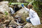 Nature, analysis and a woman with water for research, test for pollution and bacteria. Biology, sustainability and a scientist looking at a sample from a river for ecology inspection and science