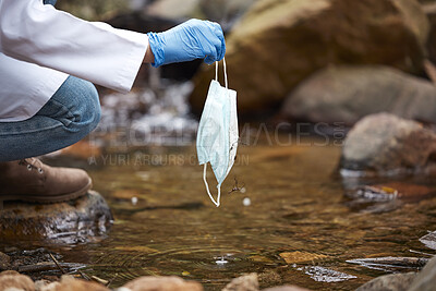 Buy stock photo Pollution, litter and face mask in river with hand of person for nature conservation, environment and safety. Covid, danger and trash with garbage in water for medical waste, healthcare and cleaning