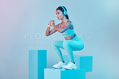 Buy stock photo Fitness, squat and woman with focus, exercise and confident person against blue studio background. Female, model and athlete with headphones, workout goal or balance for wellness or healthy lifestyle