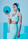 Fitness, ball and woman in studio with music for training, exercise and sports routine on blue background. Headphones, radio and indian female athlete with weight and podcast, mindset and focus 