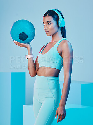 Buy stock photo Fitness, ball and woman in studio with music for training, exercise and sports routine on blue background. Headphones, radio and Indian female athlete with weight and podcast, mindset and focus 
