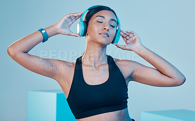 Buy stock photo Headphones, fitness and woman isolated on blue background for workout, training or exercise music. Gen z, sports and biracial person listening on audio technology, mental health or wellness in studio