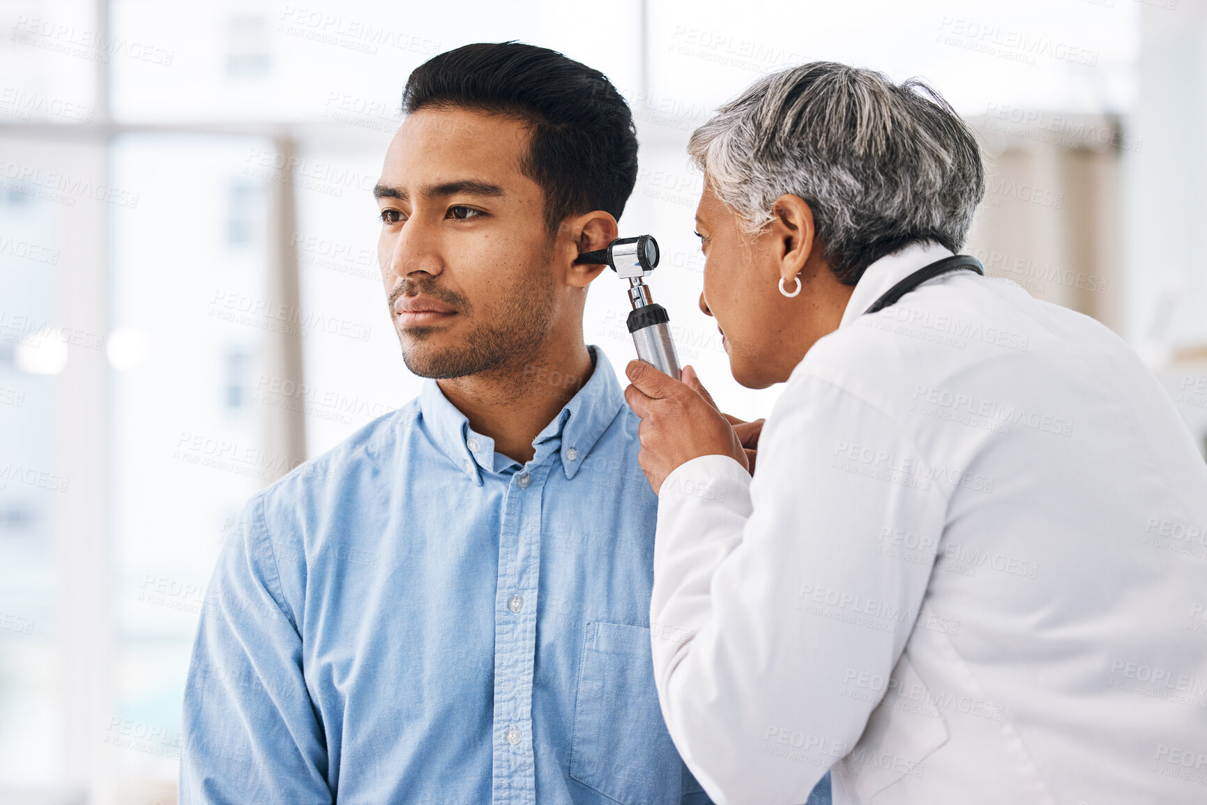 Buy stock photo Doctor check patient ear, consultation and healthcare, people at hospital with otolaryngology specialist. Man and senior physician woman with otoscope test for hearing problem and health insurance
