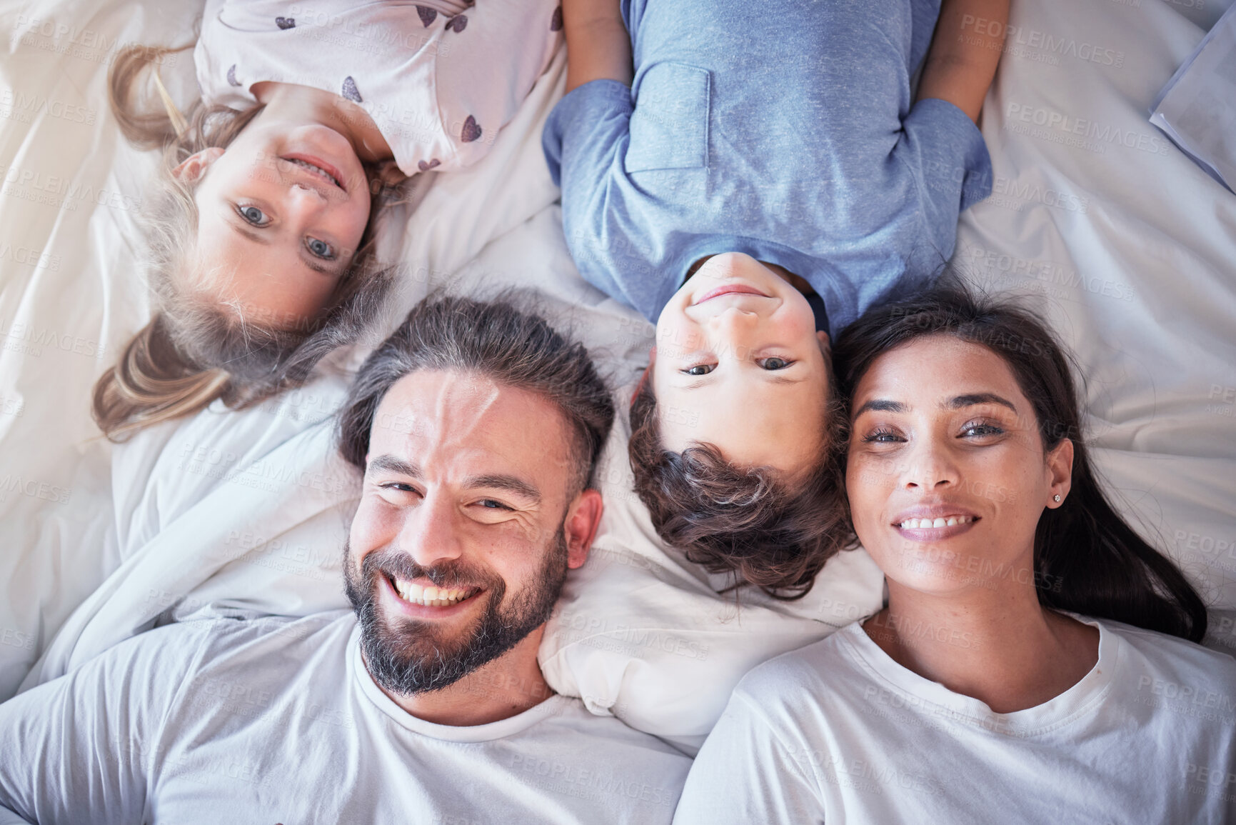 Buy stock photo Top view, smile and family on bed, love and bonding with quality time, break and relax together. Portrait, happy parents and mother with father, children and siblings in bedroom, happiness and peace