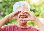 Portrait, hands and heart with a senior woman outdoor in a garden during summer for love or health. Face, emoji and shape with a hand gesture by a happy mature female outside in a park for wellness