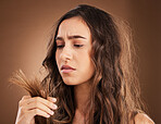 Split ends, hair damage and woman in studio for frustrated, crisis and textures with salon treatment. Beauty, repair and haircut with female model on brown background for keratin and cosmetology