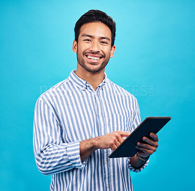 Buy stock photo Tablet, Asian man and smile portrait in a studio on social media, internet and website app scroll. Happiness, isolated and blue background with a male model reading technology for digital networking 