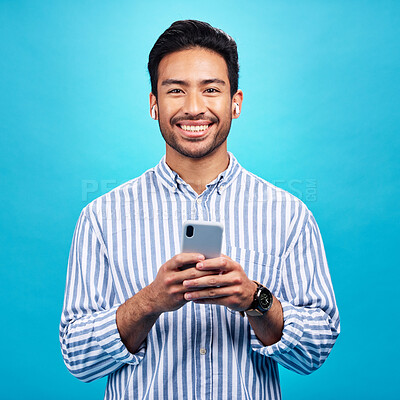 Buy stock photo Happy, portrait and a man with a phone for communication isolated on a blue background in a studio. Smile, social media update and a person typing on a mobile for app, notification reply and message