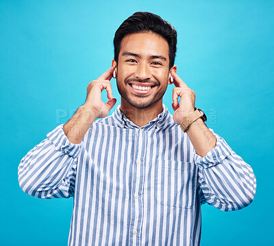 Buy stock photo Portrait, earphones and happy man with music in studio, relax and smile on blue background. Radio, face and asian male listening to podcast, streaming or audio, online or subscription while isolated