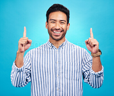 Buy stock photo Point, happy and portrait of Asian man on blue background for news, information and announcement. Advertising, studio mockup and face of excited male pointing for copy space, promo and showing sign