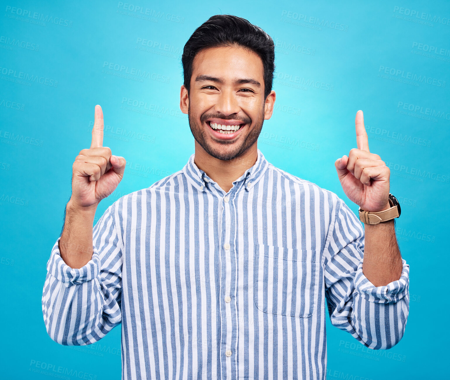 Buy stock photo Point, happy and portrait of Asian man on blue background for news, information and announcement. Advertising, studio mockup and face of excited male pointing for copy space, promo and showing sign