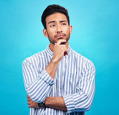 Buy stock photo Thinking, planning and future with a man on a blue background in studio to consider a thought or option. Idea, mindset and contemplation with a handsome young person looking thoughtful about a choice