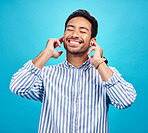Happy man, earphones and and music in studio, relax and cheerful on blue background. Radio, smile and indian male smile while listening to podcast, streaming or audio, online or subscription isolated