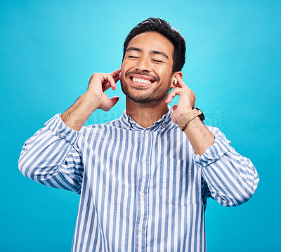 Buy stock photo Happy man, earphones and and music in studio, relax and cheerful on blue background. Radio, smile and indian male smile while listening to podcast, streaming or audio, online or subscription isolated