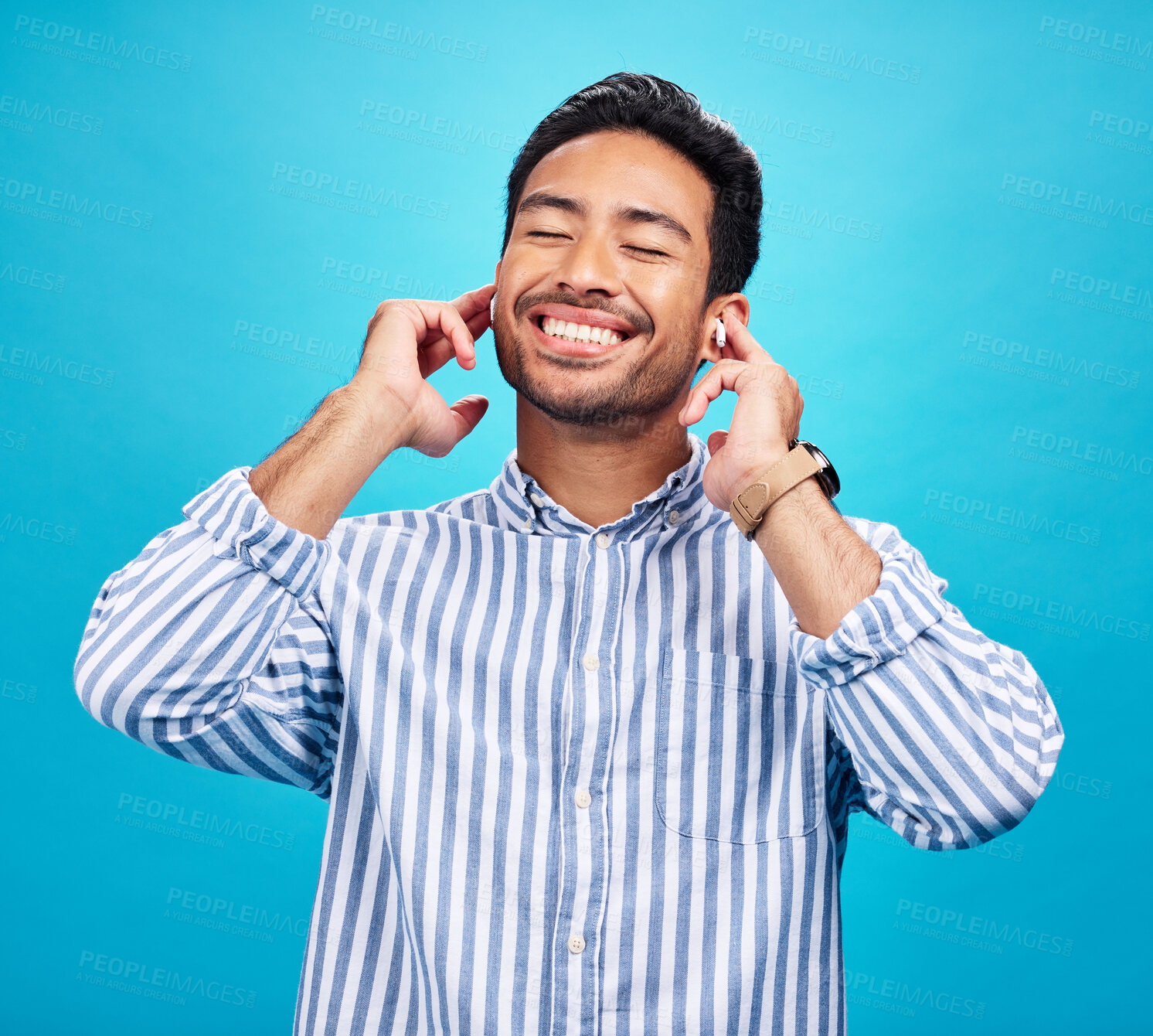 Buy stock photo Happy man, earphones and and music in studio, relax and cheerful on blue background. Radio, smile and indian male smile while listening to podcast, streaming or audio, online or subscription isolated