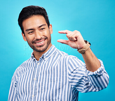 Buy stock photo Small, hand and gesture of a man with a smile in studio showing a tiny measurement. Isolated, blue background and male model show happiness and positive opinion with hands from small size sign