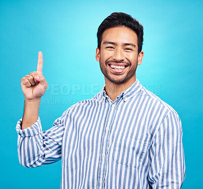 Buy stock photo Point, excited and portrait of Asian man on blue background for news, information and announcement. Advertising, studio mockup and happy male pointing for copy space, promotion and showing gesture