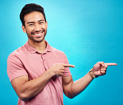 Buy stock photo Point, mockup and portrait of Asian man on blue background for news, information and announcement. Advertising, studio mockup and male pointing for branding copy space, promotion and show gesture