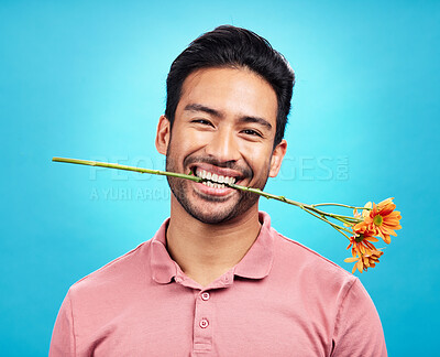 Buy stock photo Teeth, flower and portrait of man in studio for celebration, gift and romance. Funny, goofy and present with male isolated on blue background for happiness, smile and valentines day mockup