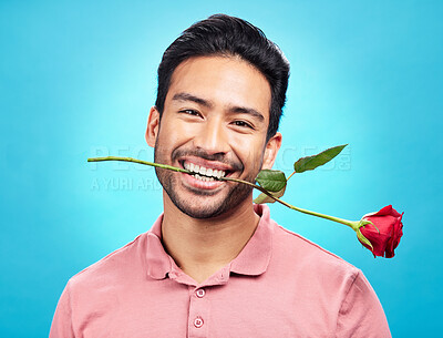 Buy stock photo Teeth, flower and rose with portrait of man in studio for celebration, gift and romance. Funny, goofy and present with male isolated on blue background for happiness, smile and valentines day mockup