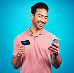 Happy man with smartphone, credit card and smile, ecommerce and fintech isolated on blue background. Online shopping, internet banking and finance with technology and male with bank app on phone