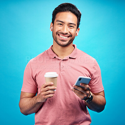 Buy stock photo Earphones, coffee and portrait of man with phone in studio isolated on a blue background. Tea, cellphone and happiness of Asian person with drink, caffeine and mobile for social media, music or radio