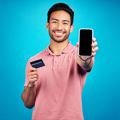 Buy stock photo Portrait, phone and credit card for online shopping with a man customer on a blue background in studio. Happy, smile and ecommerce with a young shopper using fintech to make a payment or transaction