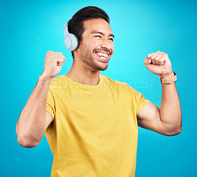 Buy stock photo Happy, music and headphones with man in studio for streaming, podcast and dance. Smile, mobile radio and technology with male isolated on blue background for listening, audio and freedom mockup