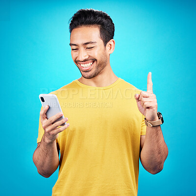 Buy stock photo Number one, phone and man isolated on blue background for online question, idea or decision on mobile app. Happy asian person or user with smartphone, internet or website and pointing up in studio