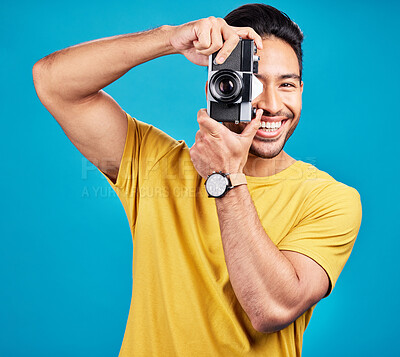 Buy stock photo Happy, photographer and man with a camera in a studio for creative or artistic photoshoot. Photography, happiness and portrait of a male person with a hobby for memories isolated by a blue background