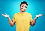 Confused, question and portrait of man shoulder shrugging and raise arms isolated in a blue studio background. Clueless, smile and young male person with doubt, whatever and doing a hand gesture