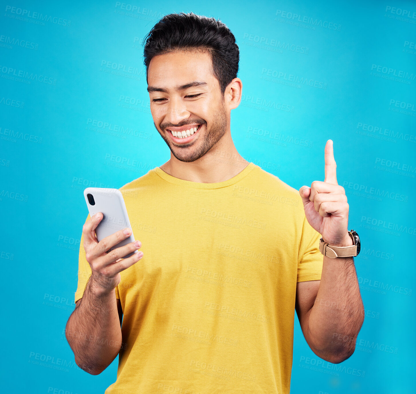 Buy stock photo Asian man, phone and man pointing up with idea, solution or question against a blue studio background. Happy person or user on mobile smartphone, internet or website and point for solving on mockup
