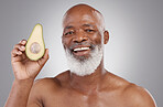 Senior black man, avocado and portrait smile for healthy skincare or natural nutrition against a gray studio background. Happy African American male smiling with fruit for skin healthcare or wellness