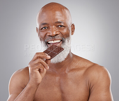 Buy stock photo Black man, senior portrait and eating chocolate isolated on a  studio background for a treat. Happy, snack smile and an elderly African model biting into a sweet candy bar for happiness and sugar