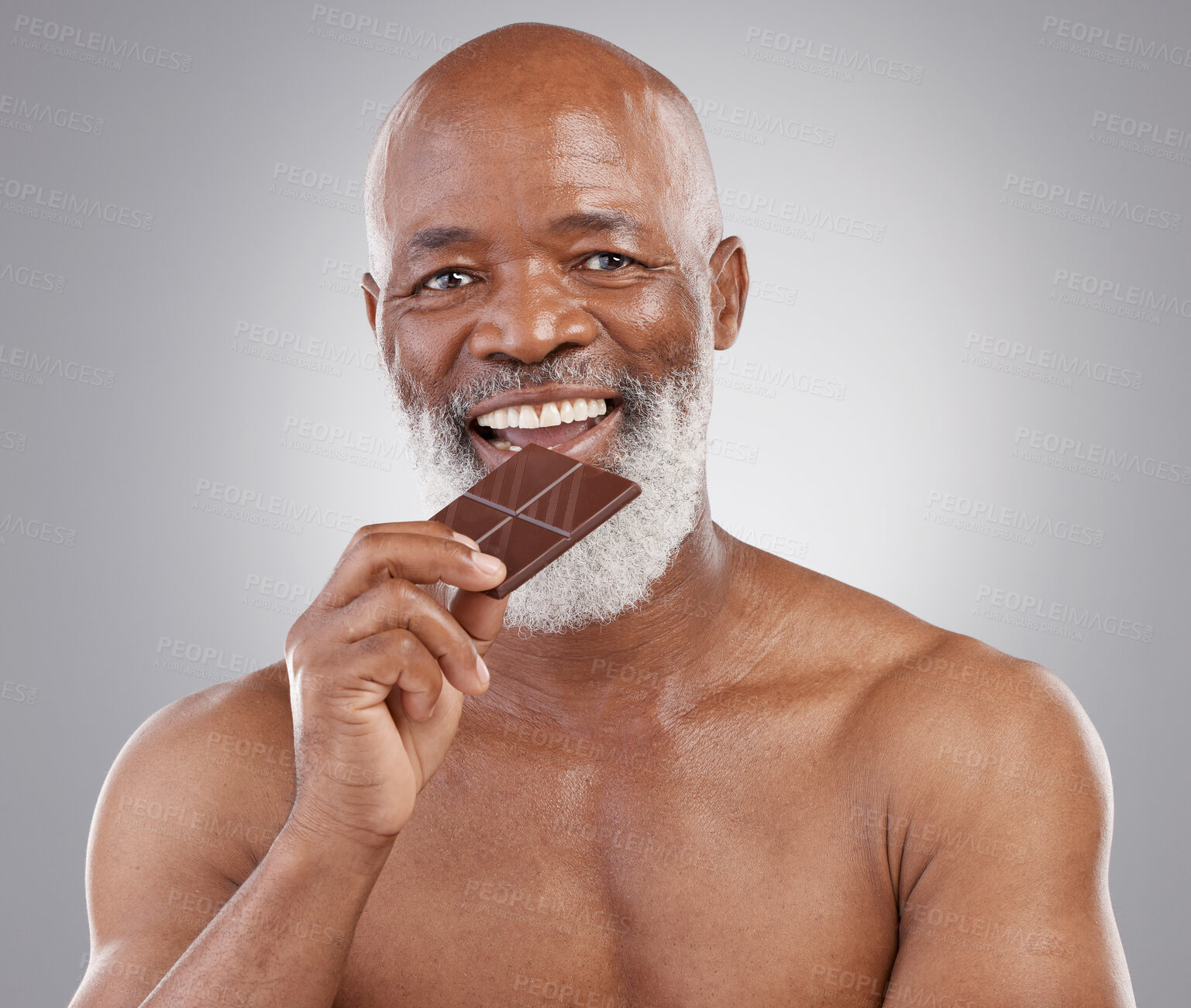 Buy stock photo Black man, senior portrait and eating chocolate isolated on a  studio background for a treat. Happy, snack smile and an elderly African model biting into a sweet candy bar for happiness and sugar