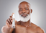 Portrait, skincare and serum with a senior man holding an antiaging product in studio on a gray background. Face, beauty and cosmetics with a mature male spraying a facial treatment for beard care