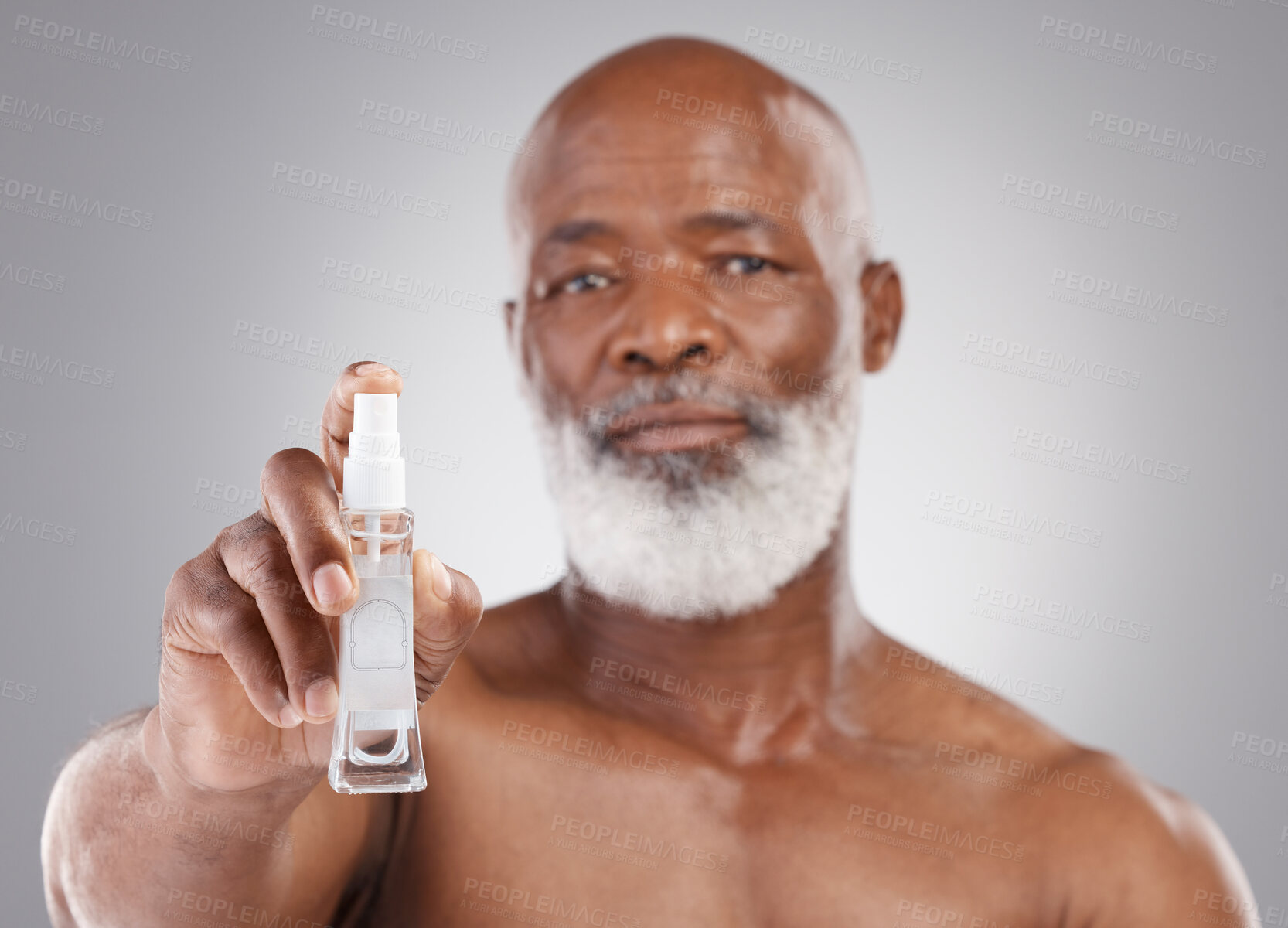 Buy stock photo Portrait, skincare and serum with a senior man holding an antiaging product in studio on a gray background. Face, beauty and cosmetics with a mature male spraying a facial treatment for beard care