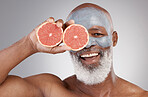 Senior black man, grapefruit and smile in skincare, vitamin C or natural nutrition against gray studio background. Portrait of happy African male with fruit and face mask for healthy skin or wellness
