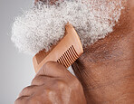 Man, hands and beard with comb in grooming, beauty or skincare hygiene against a studio background. Closeup of senior male neck and chin combing or brushing facial hair for clean wellness or haircare