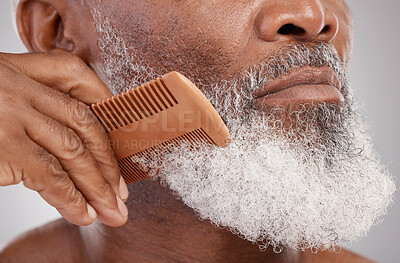 Buy stock photo Senior man, hands and beard with comb in grooming, beauty or skincare hygiene against a studio background. Closeup of African elderly male face combing or brushing facial hair for clean wellness