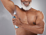 Senior black man, deodorant and spraying armpit for personal hygiene, skincare or grooming against a gray studio background. Elderly African American male applying cosmetics for fresh or clean smell