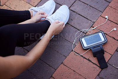 Buy stock photo Phone, fitness and footwear from above with a woman athlete sitting on the ground to tie laces. Exercise, music and getting ready for running with a female sports person outdoor for cardio training