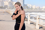 Shoulder pain, fitness woman and music of a person running by the sea with a arm injury. Workout, sports and training accident of a female runner on a exercise run and muscle bruise on arms outdoor