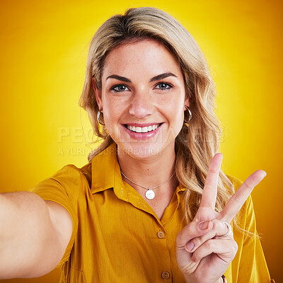 Buy stock photo Selfie, portrait and peace with a woman on a yellow background in studio looking happy. Face, smile and hand gesture with an attractive young female model showing v emoji, symbol or social media pov