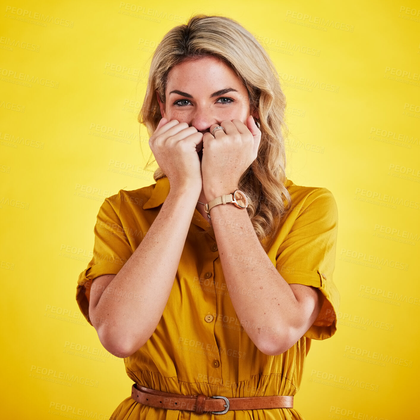 Buy stock photo Portrait, shy and woman with fist on face in studio isolated on a yellow background. Female person, introvert and covering mouth with hands, peek and hiding, secret and embarrassed with gossip.