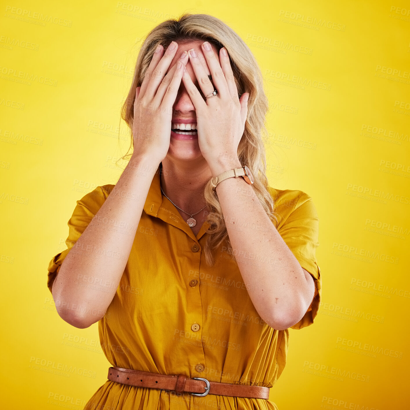 Buy stock photo Comic, funny and embarrassed with a woman on a yellow background in studio laughing at a joke. Smile, comedy and humor with a person enjoying laughter or fun while covering her face in expression