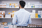 Pharmacy, medicine and back of man check shelf for medication, prescription and treatment. Healthcare clinic, drug store and male person reading boxes for medical product, supplements and antibiotics