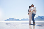 Love, hug and mockup with a couple on the beach for romance, dating or summer vacation together. Travel, ocean or view with a man and woman hugging while standing together on a coastal seashore