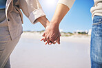 Holding hands, love and a couple walking on the beach for romance, support or a date. Content, vacation and a man and woman with affection on a walk at the ocean for commitment and trust together